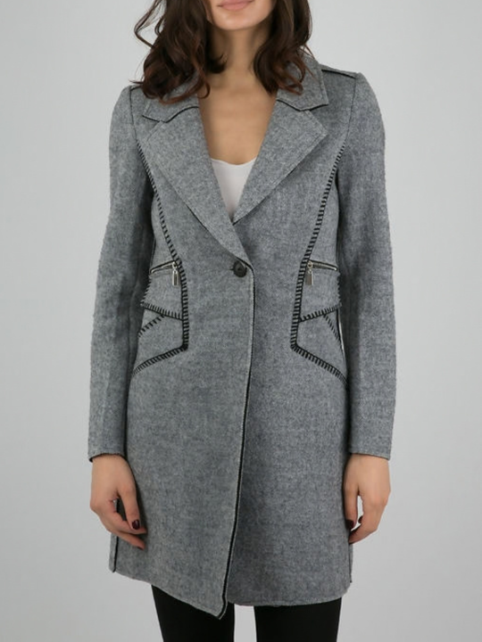 Close up. Female model stands in front of a plain background. The model wears a grey woolen coat with single front button fastening and grey tweed trim. The front of the luxe coat can be seen. 