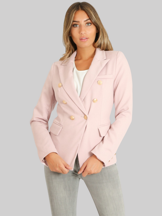 Female model wears a g double breatsted blazer with gold military buttons at the front of the blazer and the cuffs. The model has tanned skin and light brown hair, she faces the camera and has her hands in ffront of her.  She wears the double breasted blazer closed, the military gold button fastening can be seen. 