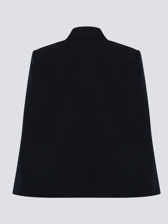Ghost manequin wears a luxe navy blazeer with a double breasted design, cape sleeves and a gold military buttons at the front of the blazer.  The ghost manequin stands with its back towards the camera. The back of the navy blazer can be seen, demonstrating the cape shape.