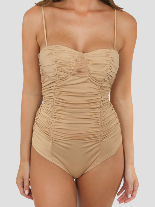 Mid length shot of models torso. Female model stands before a plain background. The model wears a nude bodysuit with a sweetheat neckline and cup detailing and adjustable spagehtti straps. The model has tanned skin, she faces forward and places her hands by her sides. 