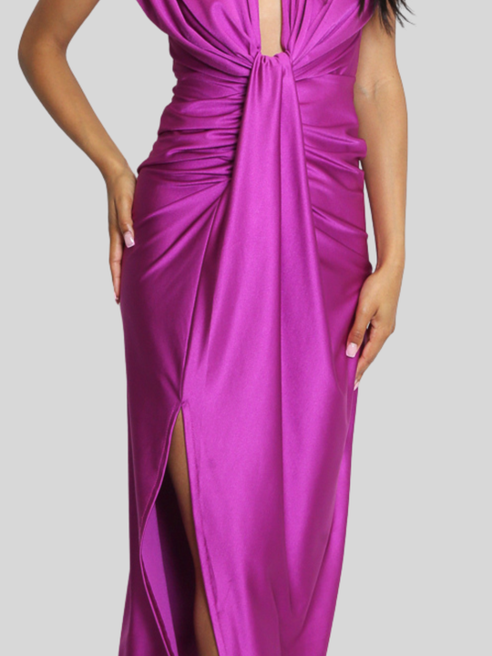 Mid torso shot. Model stands in front of a plain background, she wras a drape front fuschia occasion midi dress, which is sleeveless and has a side thigh split design. The dress has a ruched front, which can be seen. 