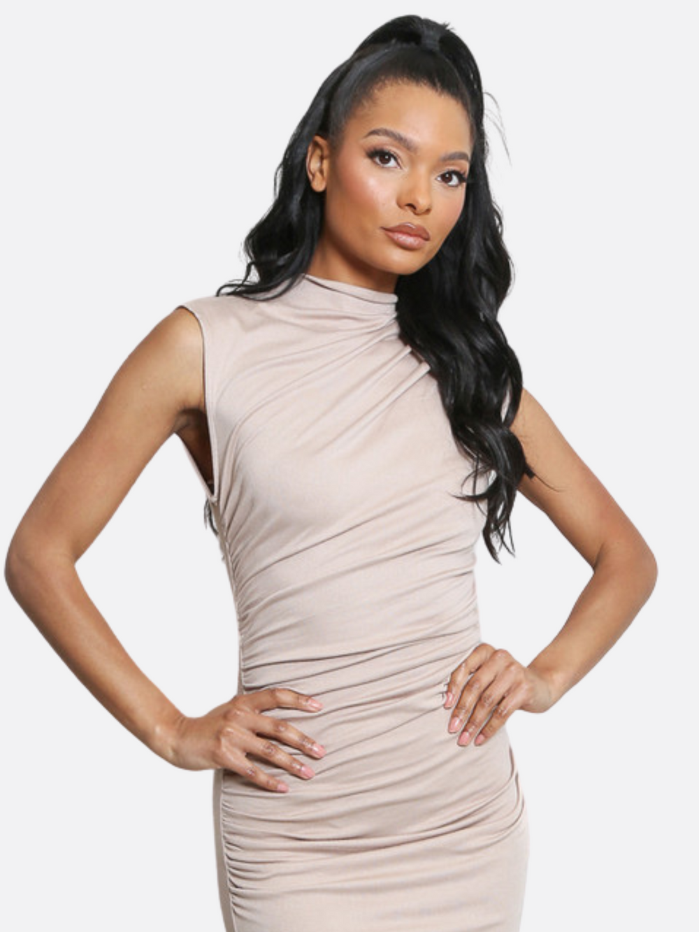 Model wears a sleeveless long taupe midi dress with a mock neck and drape front. The taupe midi dress has a stretch fit. The model has light brown skin and long black hair,  she  faces the camera and places both hands on her hips. 