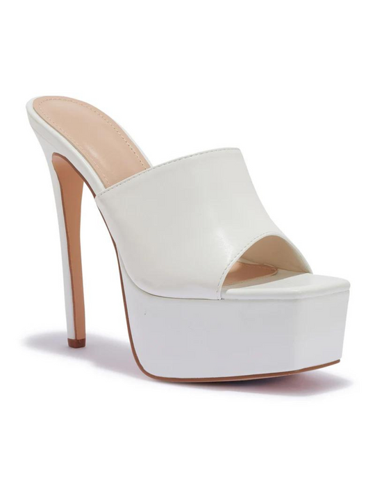 White heeled mules that have a thick platform base and stiletto shoes. The picture shows the shoe at a 120 degree angle. The side of the shoe and the tall stiletto shoe can be seen. 