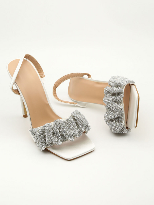 High-heeled sandals with decorative straps on a white background
