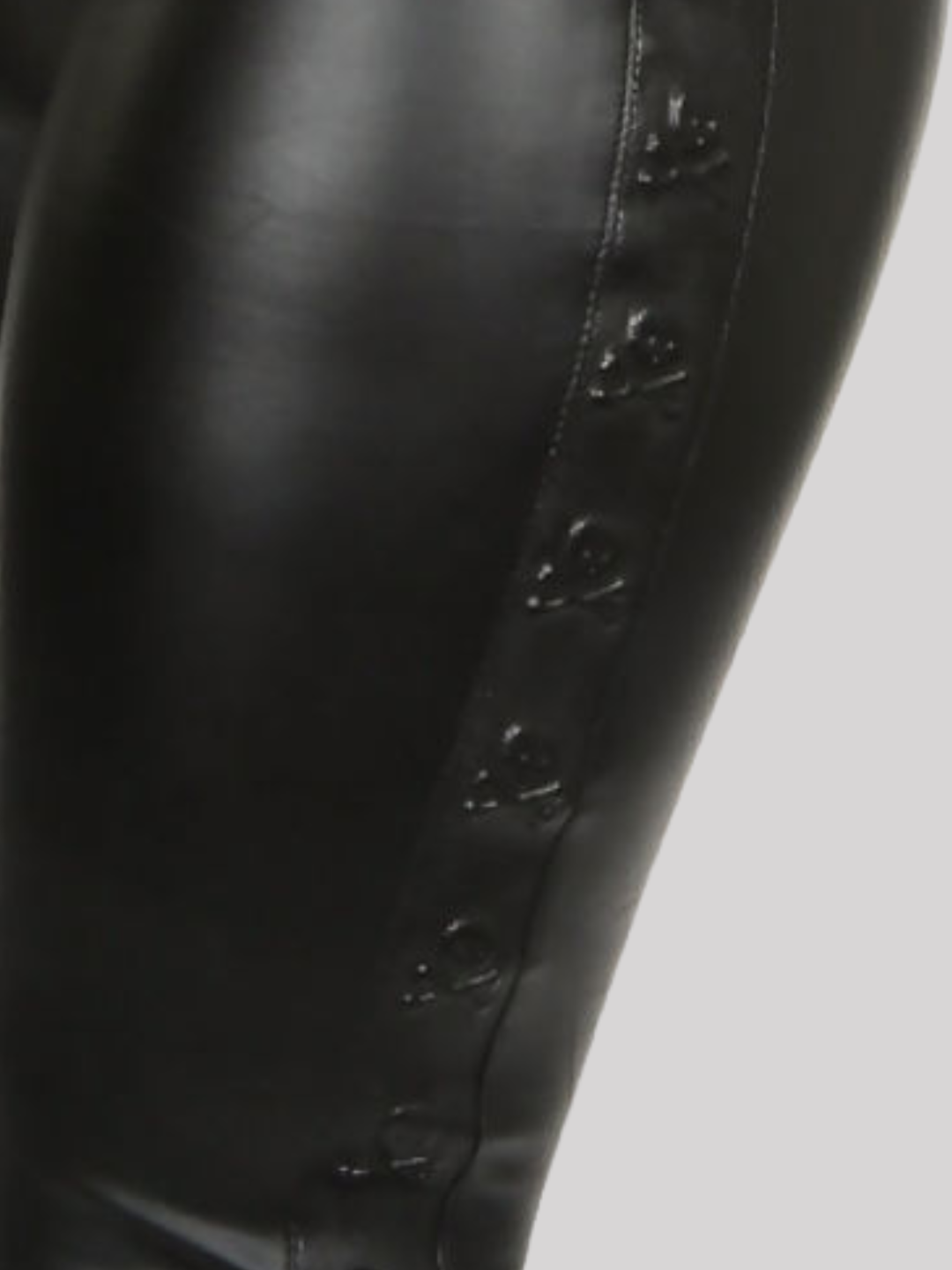 Close up. Black faux leather wet look leggings, with a skull embossed side panel. 