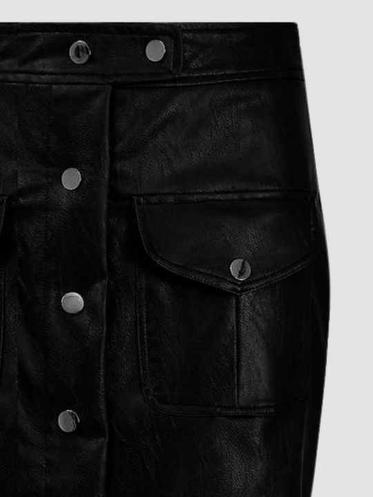 Close-up of a black faux-leather skirt featuring a buttoned front closure, a side flap pocket with a metal snap, and a waistband with snap buttons, shown against a light gray background.