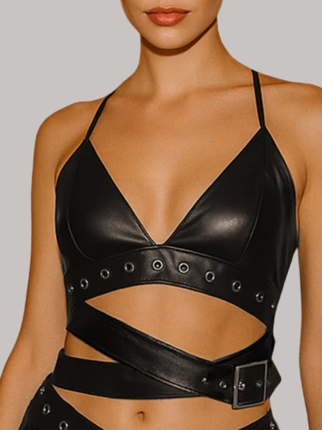 Close up shot. The model wears a black pu leather crop top and matching mini skirt design. The crop top set has a belted detaining. 