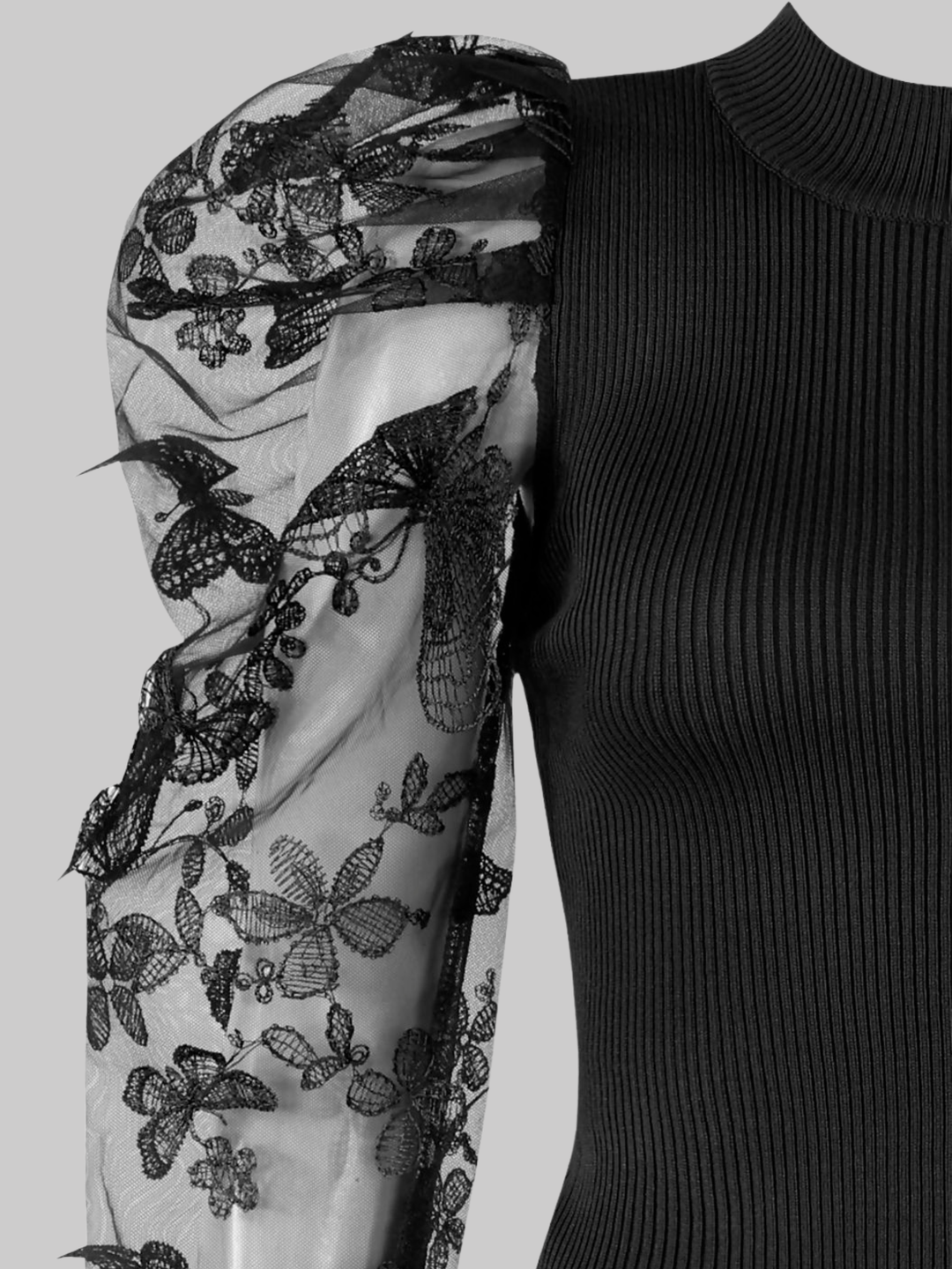 Close up of the sheer sleeve. Ghost mannequin wears a black high neck jumper, with sheer sleeves and an embroidery crocheted design.  The intricate embroided pattern can be seen. 