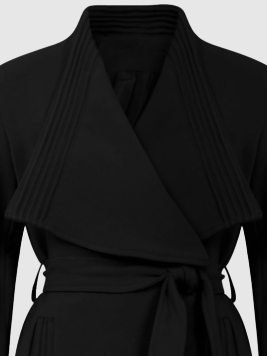 Mid Shot. Ghost mannequin stands in front of a plain light grey background. The ghost mannequin  wears a black wrap coat, with a belted waist fastening. The top of the coat can be seen, including the wrap front.