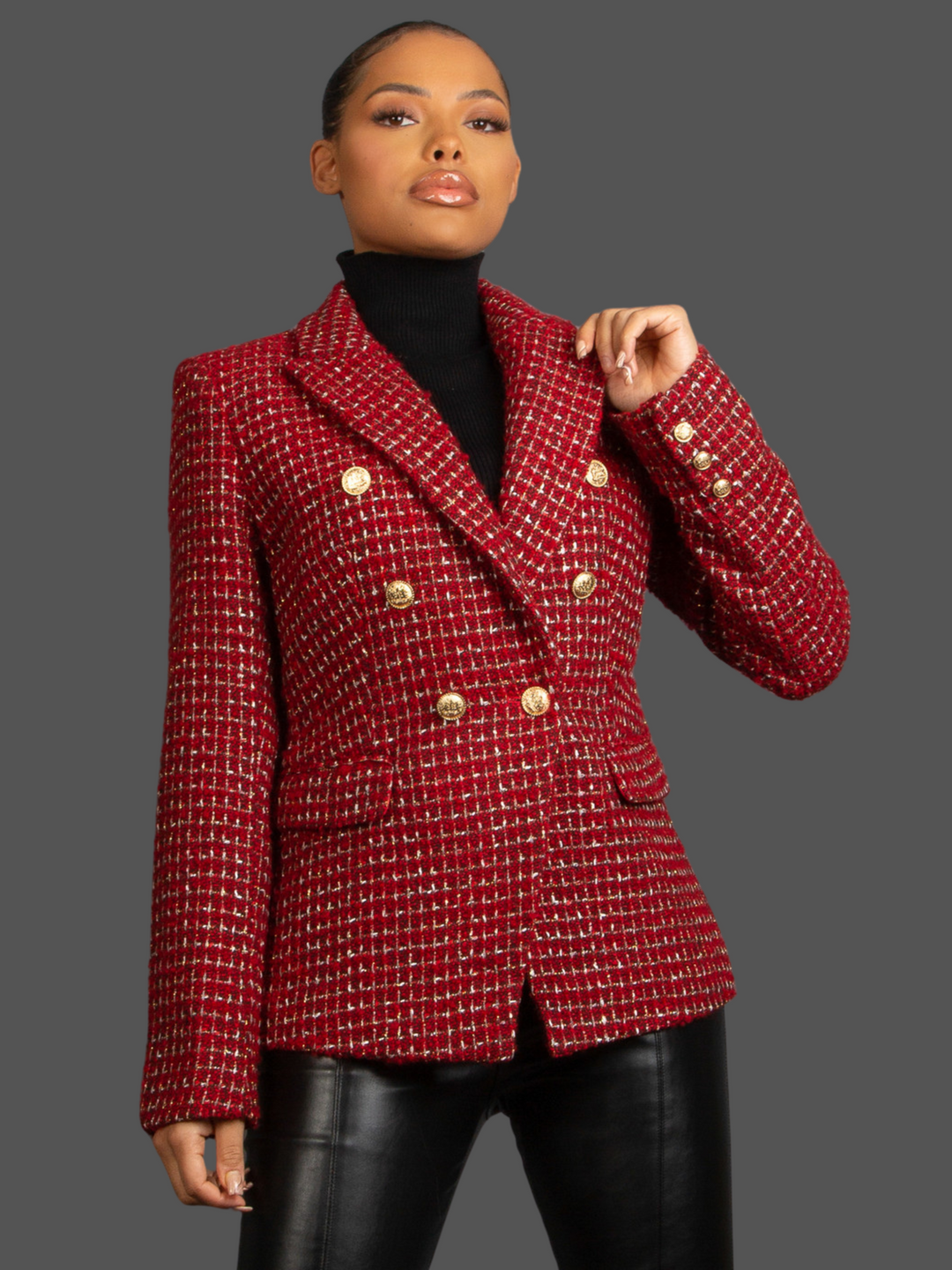 Model wears Red Wine Double Breasted Tweed Blazer, With Metallic Yarn Shimmer and Military Gold Buttons. The model as light brown skin and her hair pulled back into a ponytail. The model faces the camera, she places one hand by her ide and the other on the lapel. 