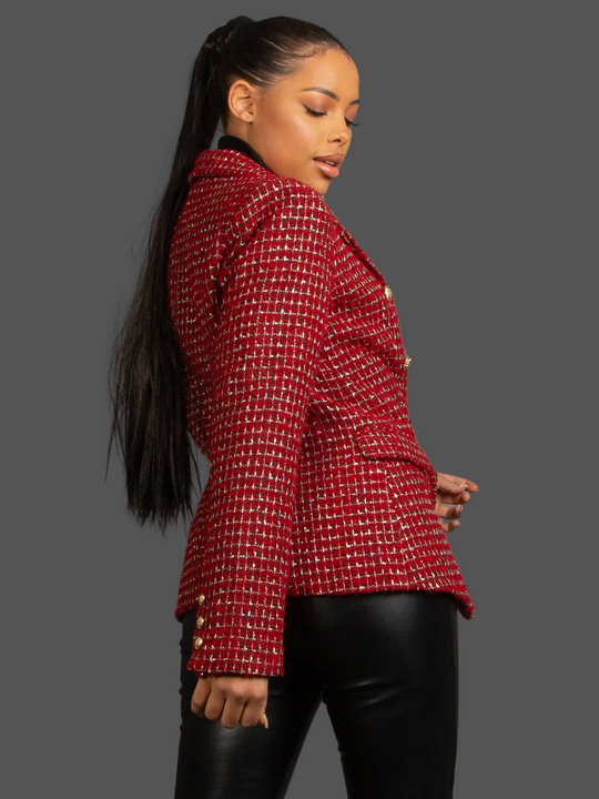 Model wears Red Wine Double Breasted Tweed Blazer, With Metallic Yarn Shimmer and Military Gold Buttons. The model as light brown skin and her hair pulled back into a ponytail. The model turns to the side and looks down, the back and side of the blazer can be seen. 