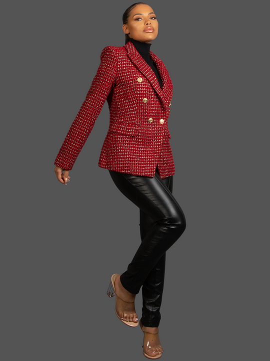 Full length shot. Model wears Red Wine Double Breasted Tweed Blazer, With Metallic Yarn Shimmer and Military Gold Buttons. The model as light brown skin and her hair pulled back into a ponytail. Model wears a faux leather trousers and eels, she bends one knee and stretches her arm out, the front and side of the blazer can be seen. 