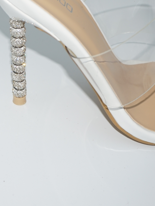 A closeup of the shoes diamante heel and perspex strap that goes across the shoe.