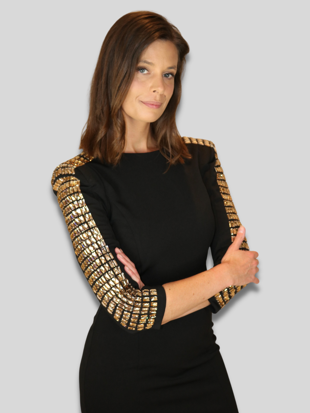 4ever Stunning Deluxe Premium black midi dress with gold rhinestone jeweled arms and chunky gold back zip fastening. Model faces the camera and folds her arms. Her rhinestone sleeved arms are visible.