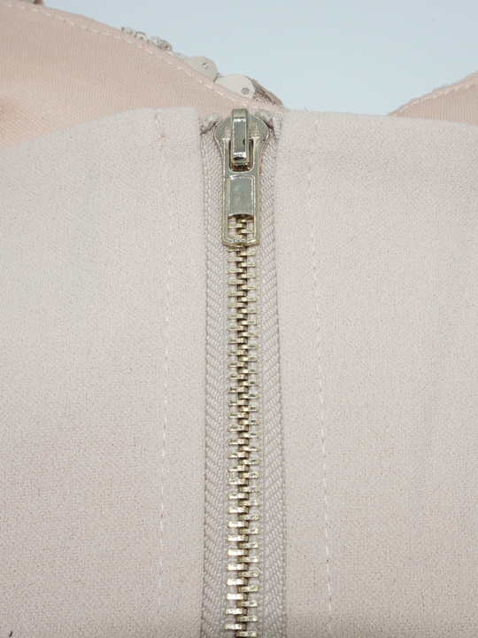 Closeup of the chunky gold zip fastening that is positioned to the rear of the bralette. 