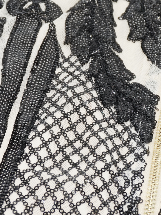 Closeup of the cream and black sequined material and chunky zip. 