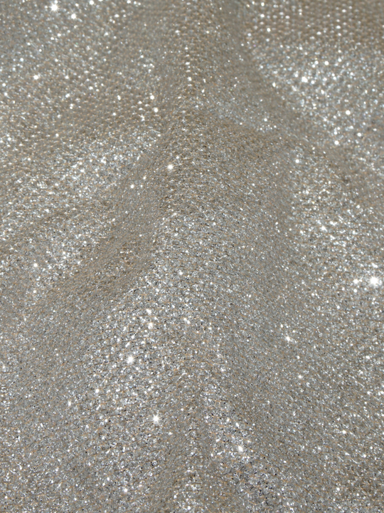 Close up of  micro mini long sleeved gold beige glitter dress with long sleeves.  The closeup demonstrates the sparkled beige glitter material of the dress.