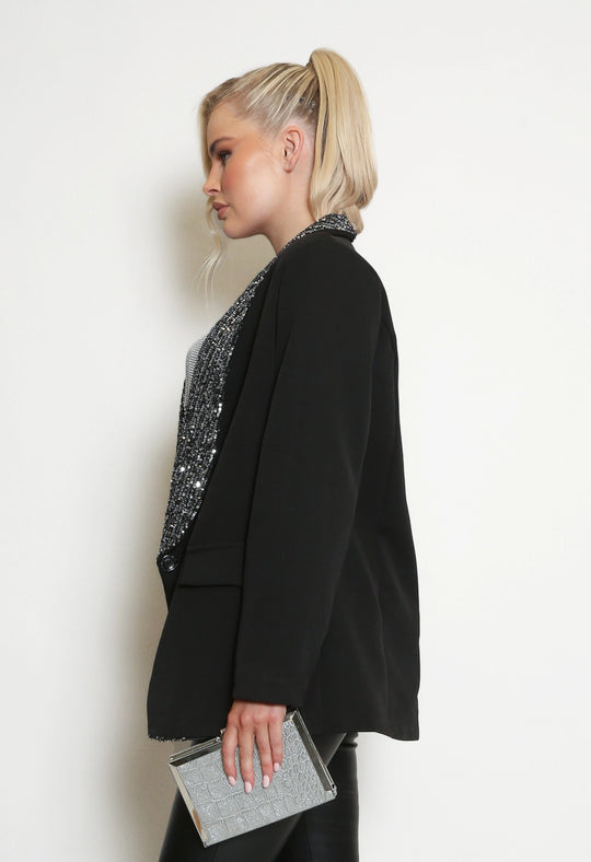 Deluxe Premium Range, Light Weight Black Blazer With Sequin Lapel Trim,  model stands to the side and the blazer can be seen from the side profile. The Sequin lapel is visible.
