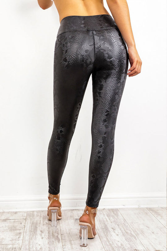 Model wears snake skin leggings with high waisted panelling. The snake skin pattern is visisble.  Model stands with her back to the camera.
