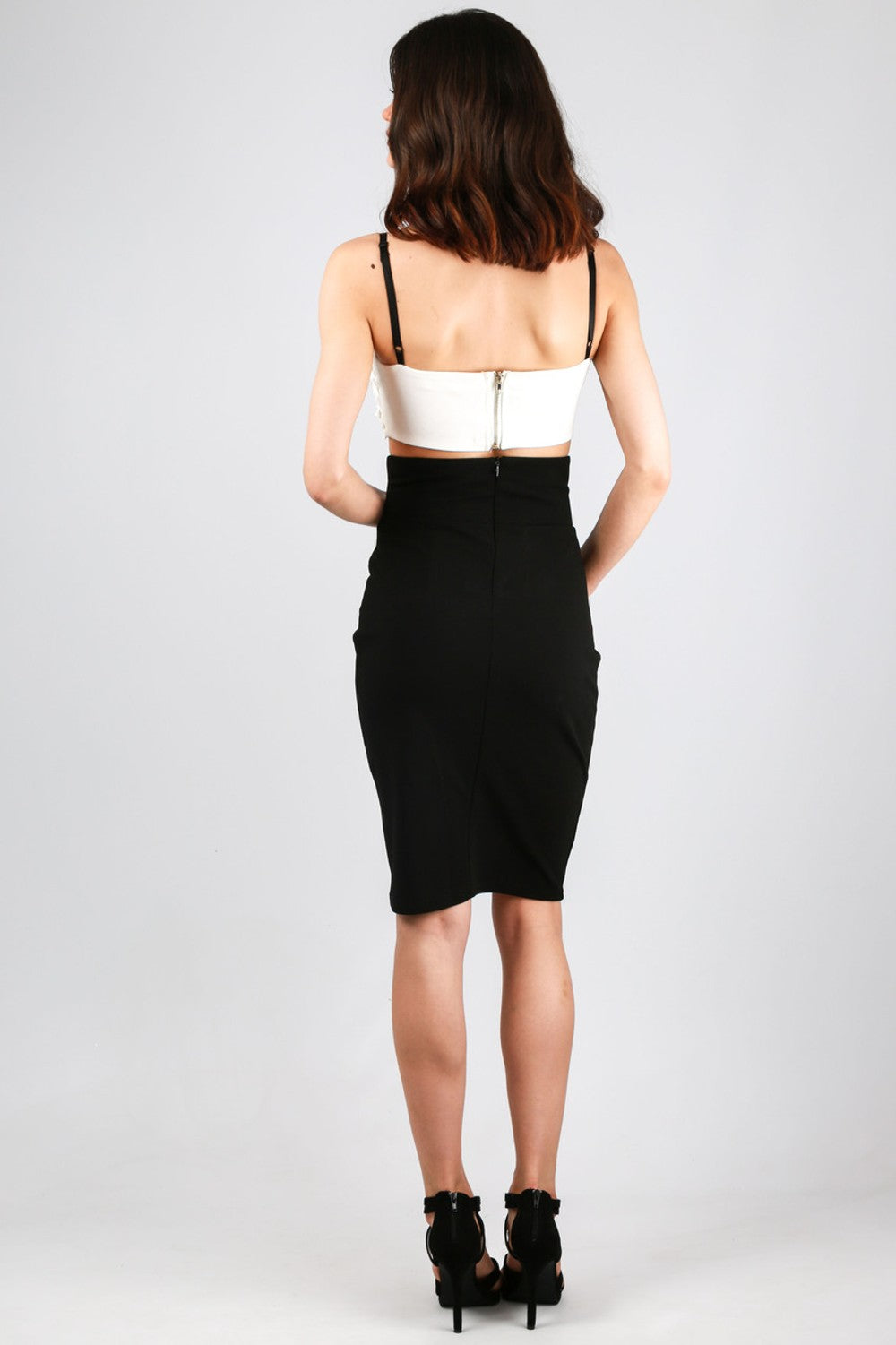 Model wears white sequinned bralette with a sweat heart bust. The bralette has black straps and a back chunky zip fastening. Model stands with her back to the camera. The chunky zip fastening to the rear is visible.