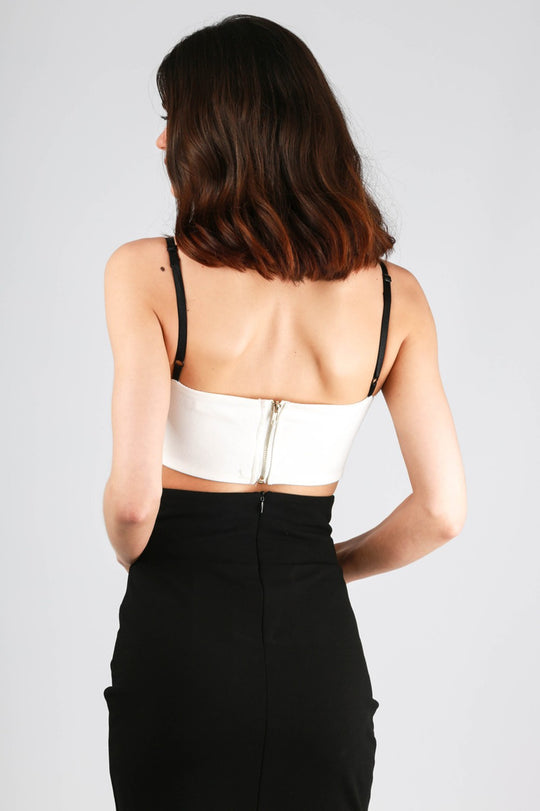 Model wears white sequinned bralette with a sweat heart bust. The bralette has black straps and a back chunky zip fastening.  The back of the model  is shown, the chunky zip fastening  is visible.