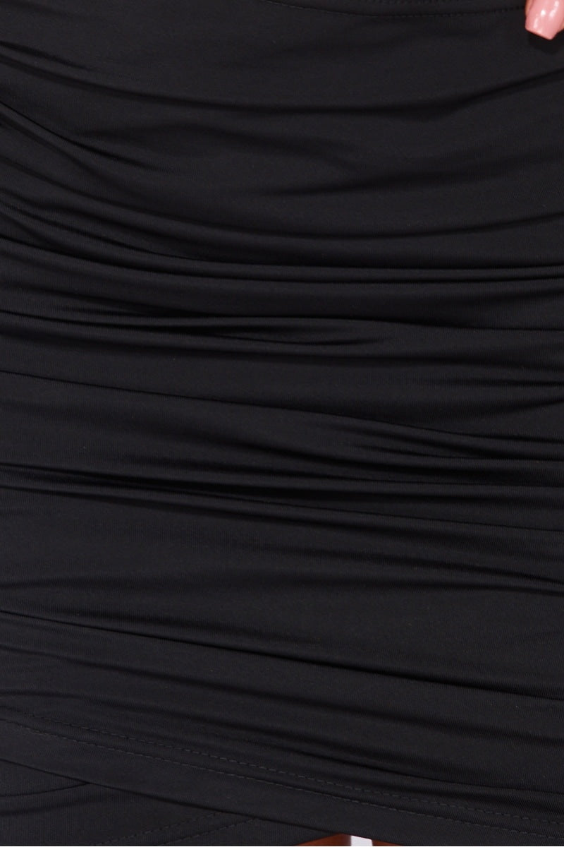 Black slinky bodycon dress with cut out mid section with cross over straps. The dress has a multiway function, you can wear it as a halter neck cross strap or as a standard halterneck. Model wears the halterneck as a cross neck halter. The picture shows a closeup of the slinky material. 