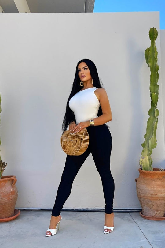 Model wears cream slinky double layered bodysuit. Model holds a basket bag and wears black denim jeggings. 