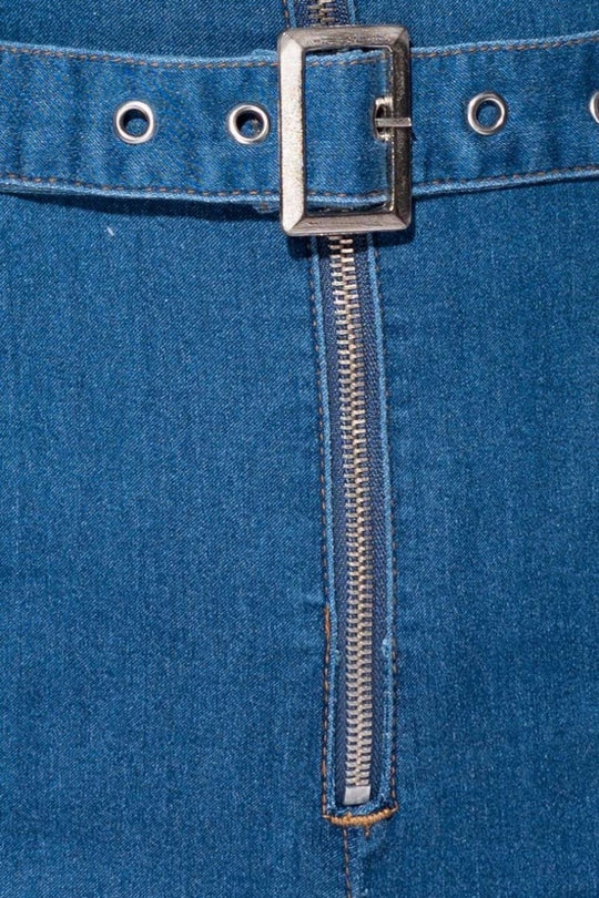 Closeup of the denim material. The silver zip and denim belt is visible. 