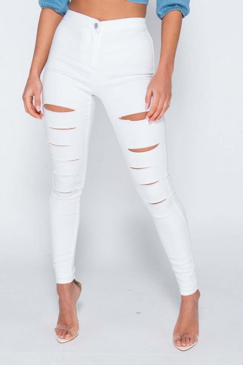 Model wears white jeggings with slash front detailing.  Model stands with one leg to the side. 