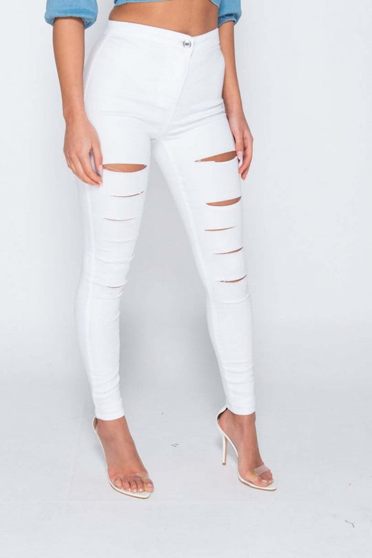 Model wears white jeggings with slash front detailing.  Model stands  to the side.