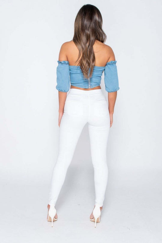 Model wears white jeggings with slash front detailing. Model  stands with  her back to the camera, the  functional back pockets are visible. Model stands with her hands by her sides.