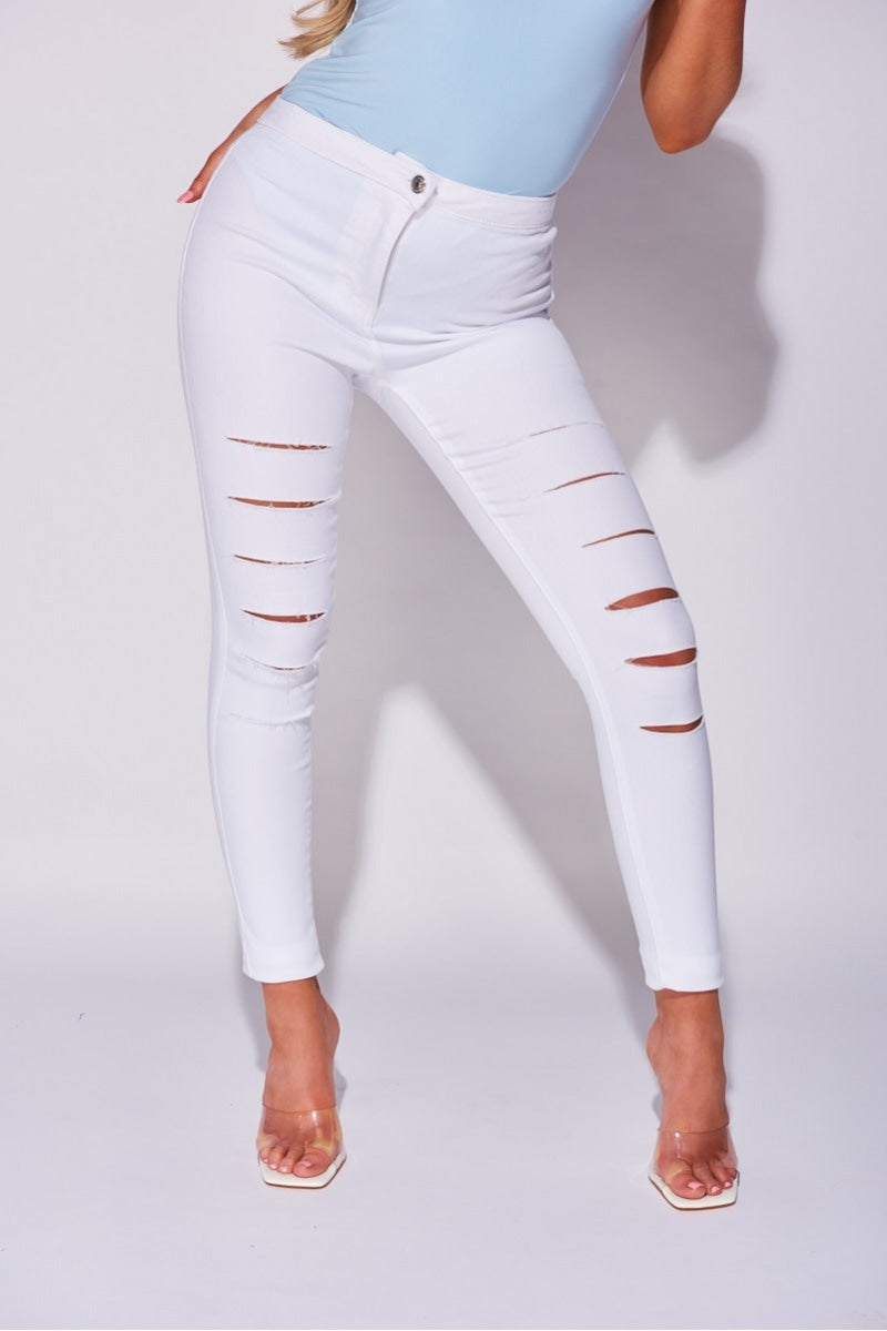 Model wears white jeggings with slash front detailing.  Model stands with one leg to the side.